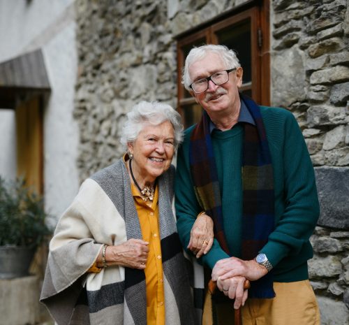 Happy senior couple posing near old countryside house.